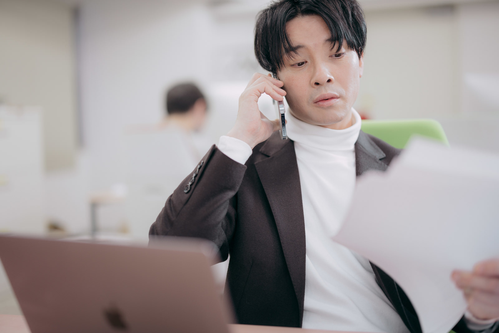 電話で確認しながら書類を読む日本人男性の写真